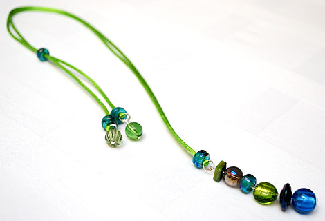 Harlequin peacock blue/green long drop pendant - Funky and bright, this pendant is designed to be worn long, but can be adjusted in length using a sliding bead. Beautiful peacock colour beads hang from silky ribbon cord.