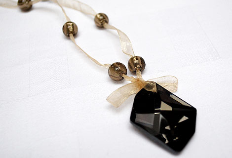 Janice long pendant - This stylish multi-faceted black glass pendant hangs from gold organza ribbon, tied in a small bow and strung with grey/gold glass beads.