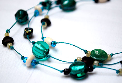 Claire green three-tiered necklace - Beautiful blue green mixed glass and foil beads interspersed with small chocolate brown, heart-shaped beads. Strung and knotted onto dark blue thread.