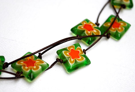 Spangle green 3-tiered necklace - Eye-catching bright green square glass beads with orange flower pattern. Strung in three rows on to knotted dark brown cord. Lobster clasp.